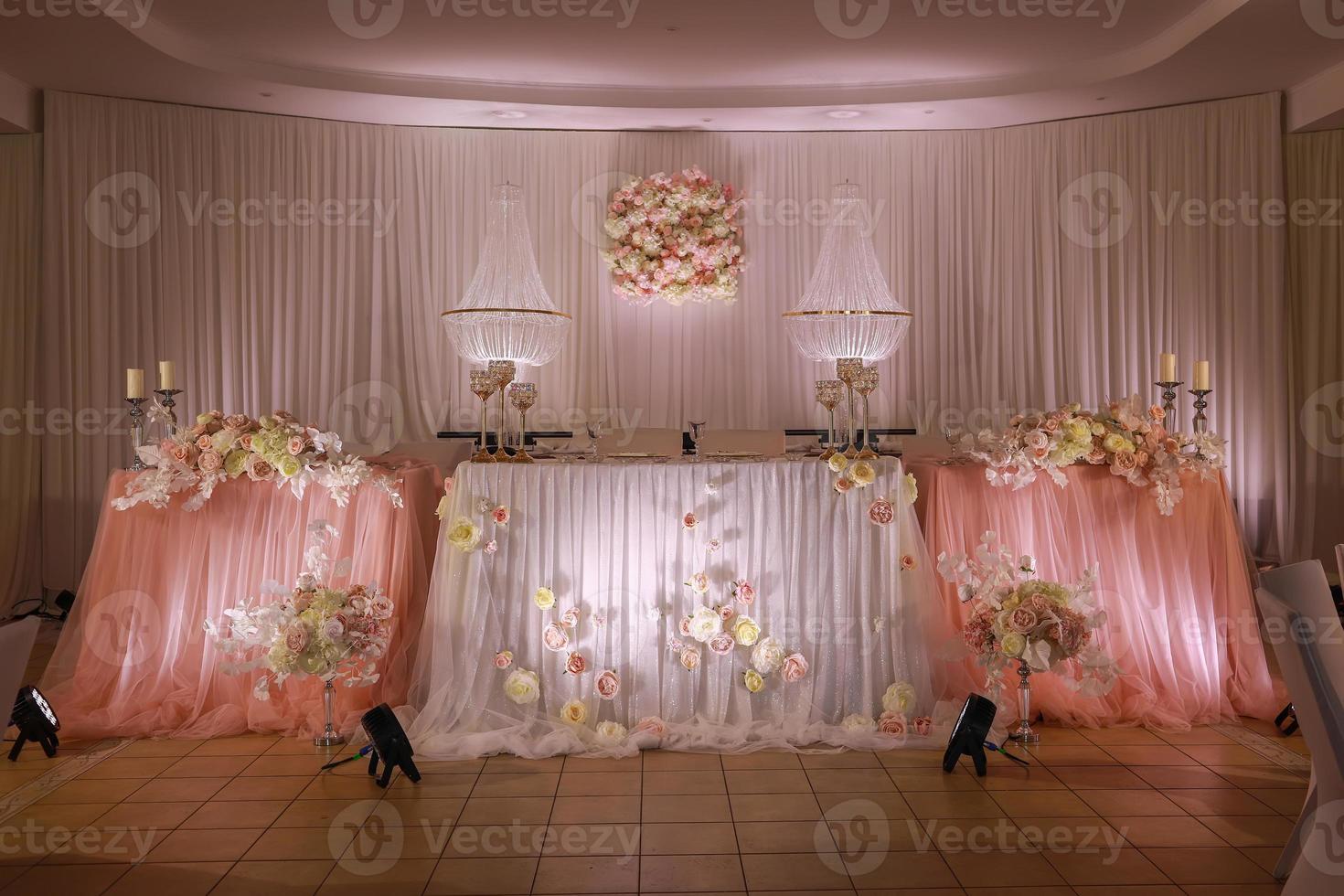 festivo nozze tavolo decorazione con cristallo lampadari, d'oro candelieri, candele e bianca rosa fiori . elegante nozze giorno foto