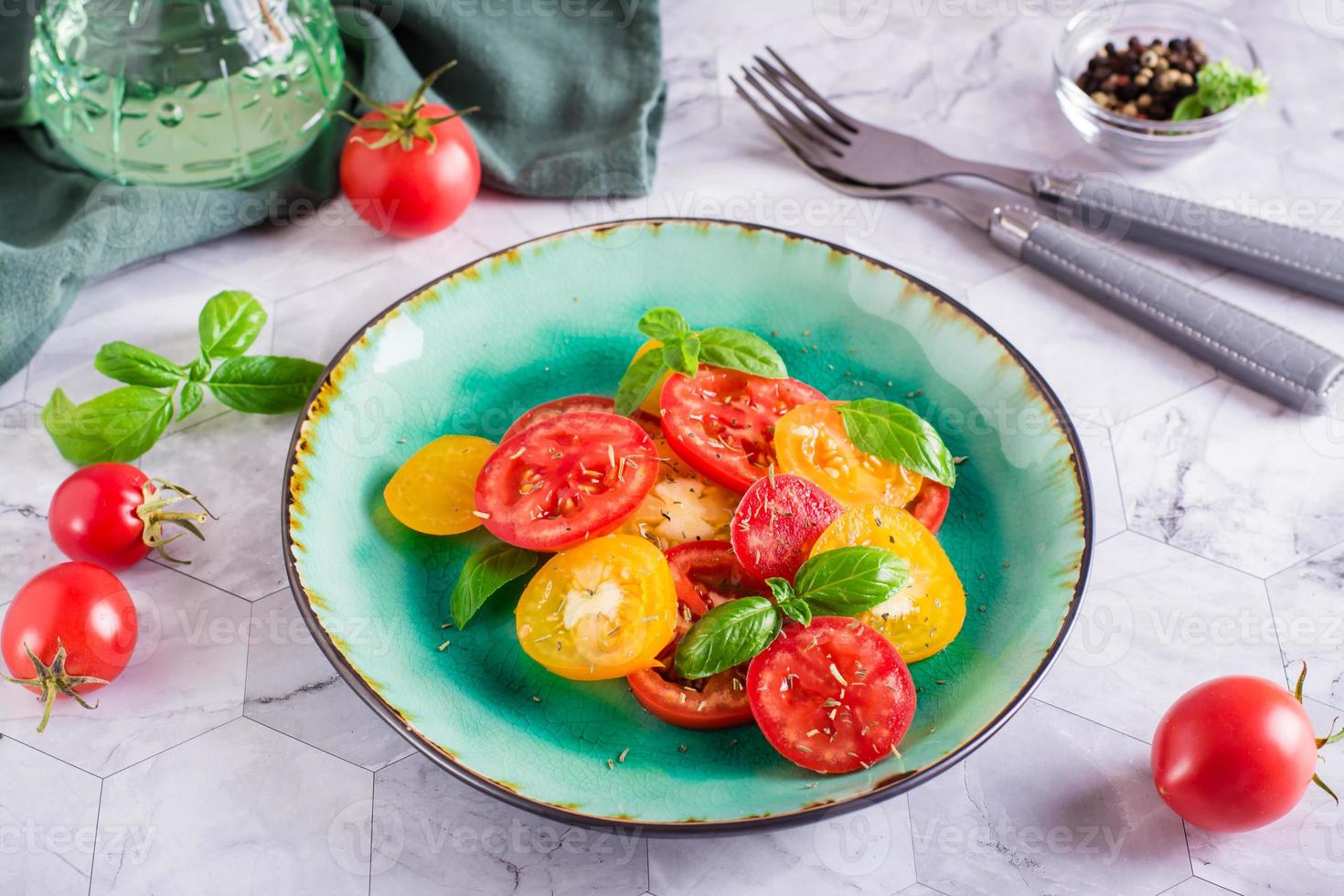 fresco insalata di giallo e rosso pomodori con basilico le foglie su un' piatto su il tavolo foto