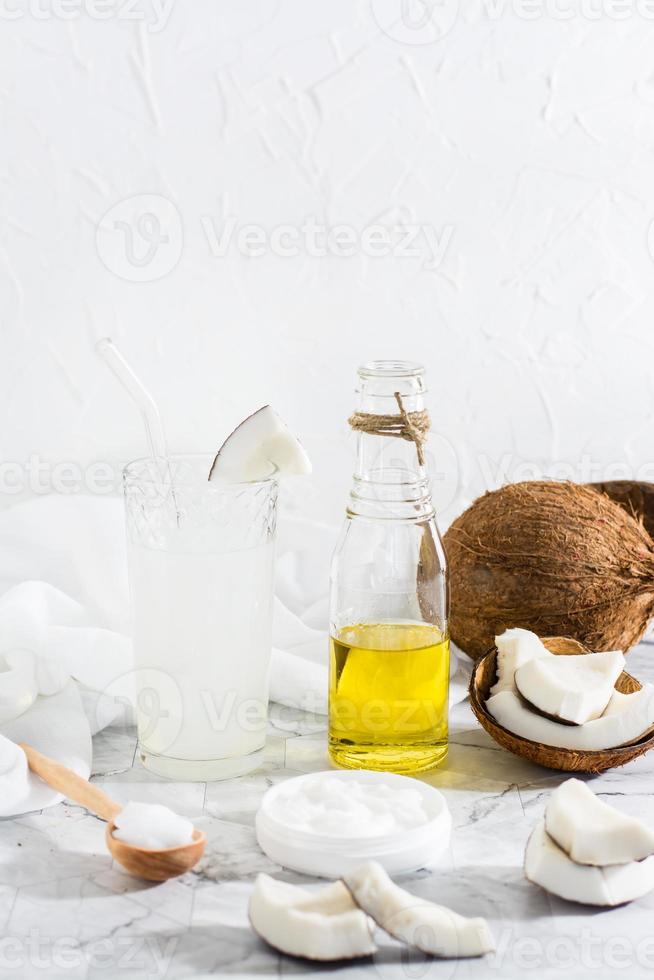 Noce di cocco prodotti - Due tipi di olio e latte e pezzi di Noce di cocco su il tavolo. verticale Visualizza foto