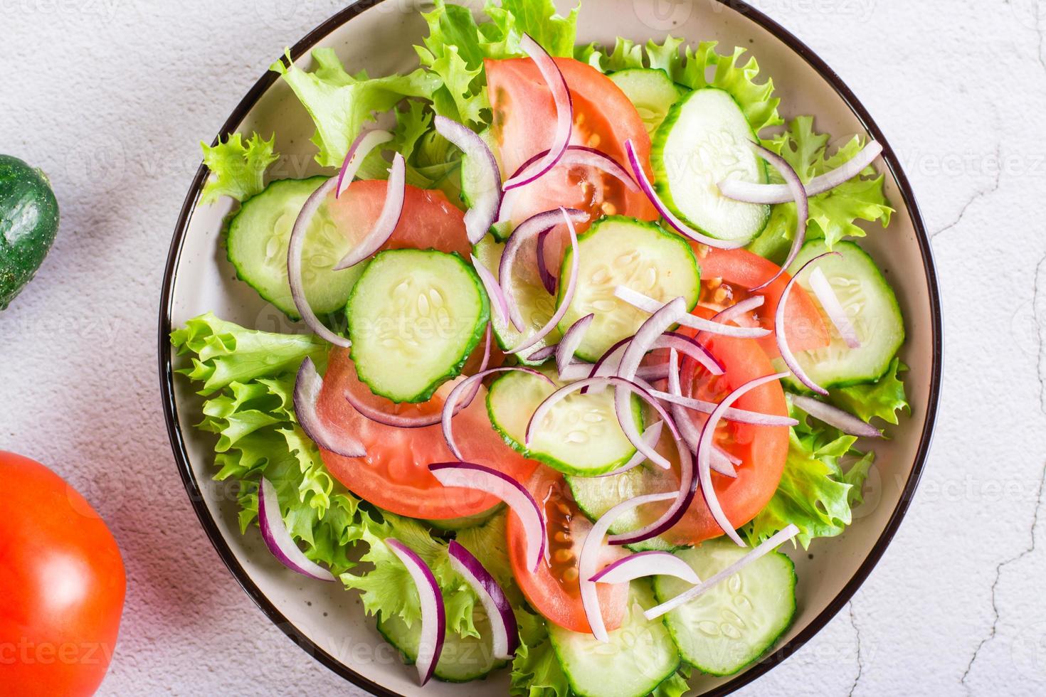 insalata di cetrioli, pomodori e cipolle su lattuga su un' piatto. vegetariano cibo. superiore Visualizza. avvicinamento foto