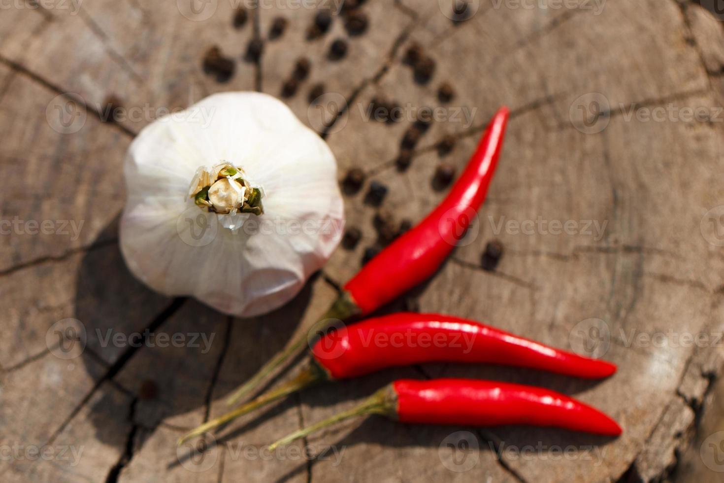 testa di aglio e rosso caldo peperoni su un' di legno sfondo avvicinamento di un' tavola foto