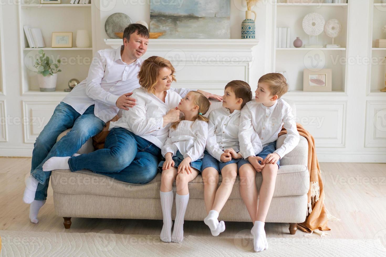 grande contento famiglia seduta su divano nel luminosa vivente camera. famiglia ritratto foto