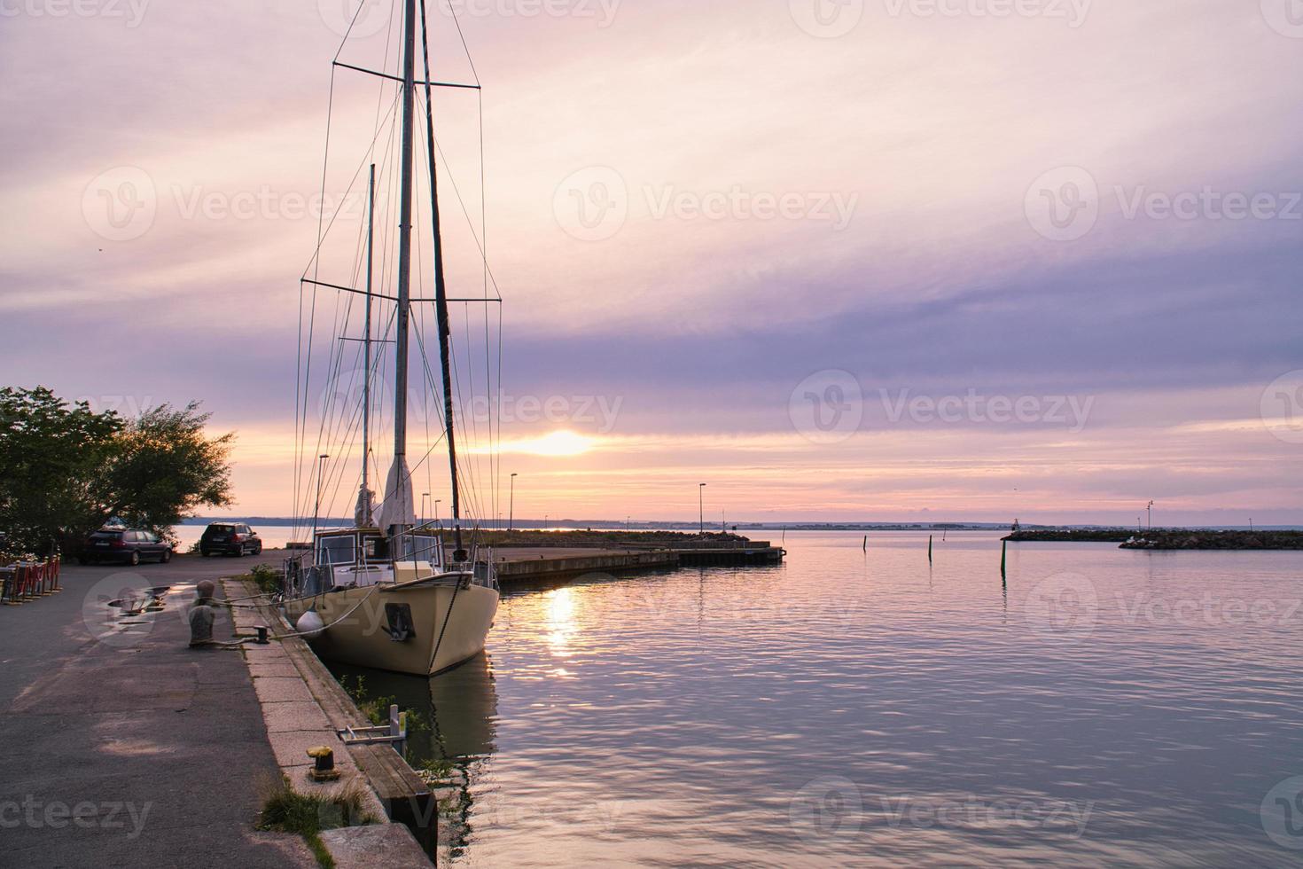 andare in barca nave nel il porto di lago vaetter a tramonto. faro nel il sfondo foto