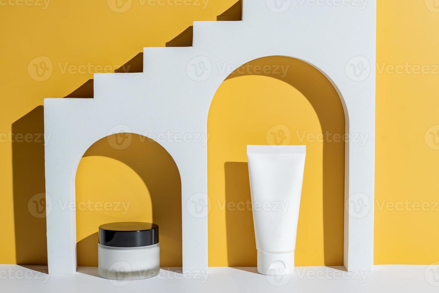 geometrico forme per pelle cura cosmetici presentazione. archi In piedi su un' giallo sfondo. presentazione di diverso viso crema pacchetto - vaso e spremere tubo. modello. senza marchio pacchetto foto