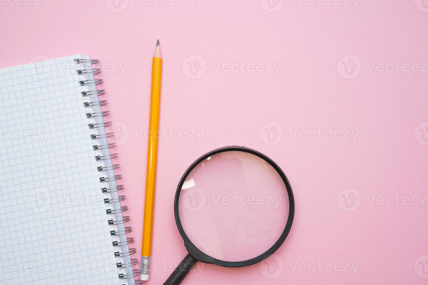 ingrandimento bicchiere, matite e un' vuoto bianca bloc notes su un' primavera su un' rosa foto