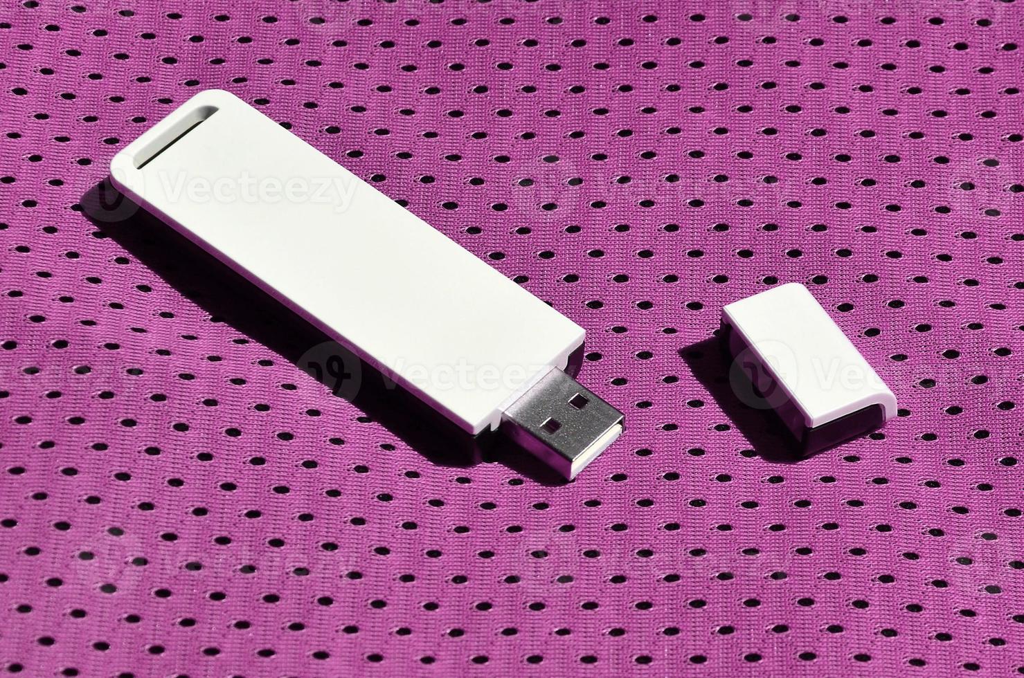 un' moderno portatile USB Wi-Fi adattatore è posto su il viola abbigliamento sportivo fatto di poliestere nylon fibra foto