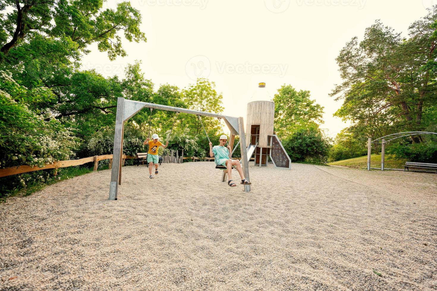 Due fratelli swing nel figli di terreno di gioco giocattolo impostato nel pubblico parco. foto