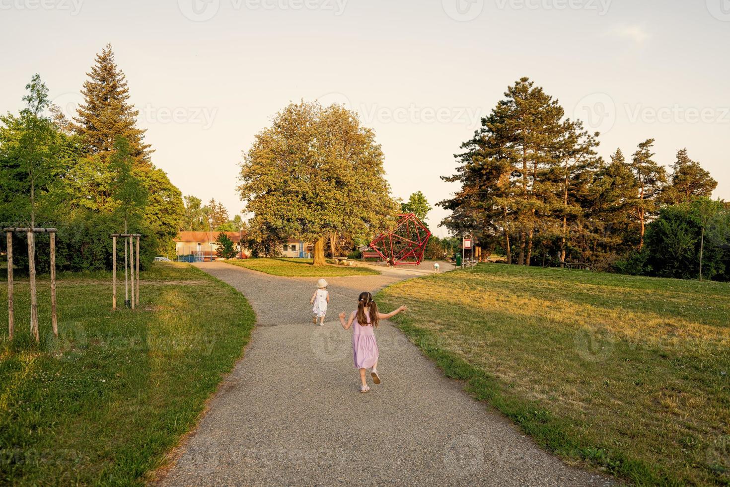 indietro di Due sorelle correre per terreno di gioco nel parco. foto