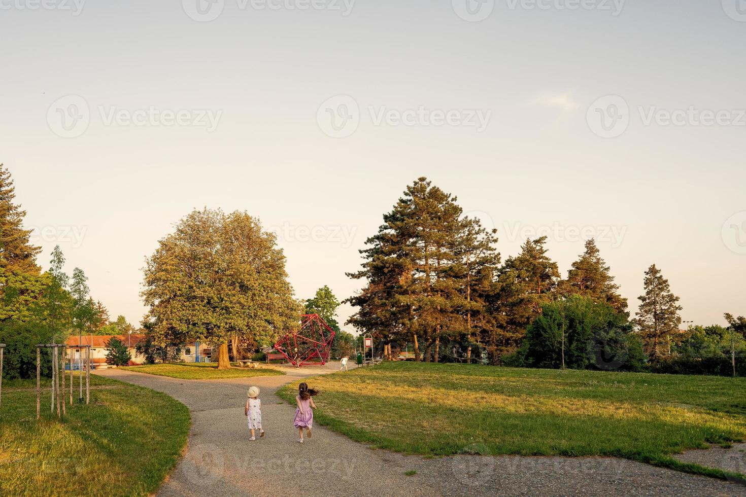 indietro di Due sorelle correre per terreno di gioco nel parco. foto