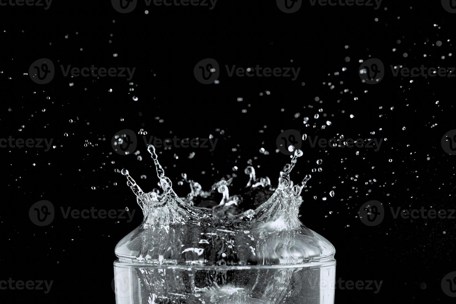 superiore di trasparente bicchiere e acqua spruzzo isolato su nero sfondo. foto