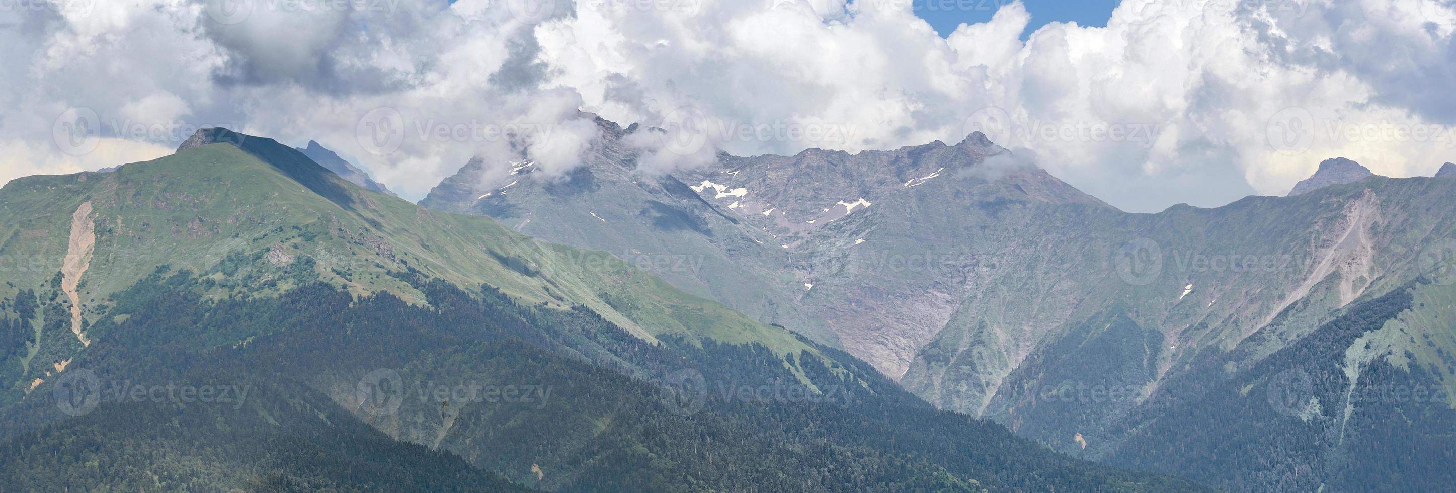 Visualizza di il verde montagne illuminato di luminosa luce del sole su il sfondo di grande bianca nuvole. foto