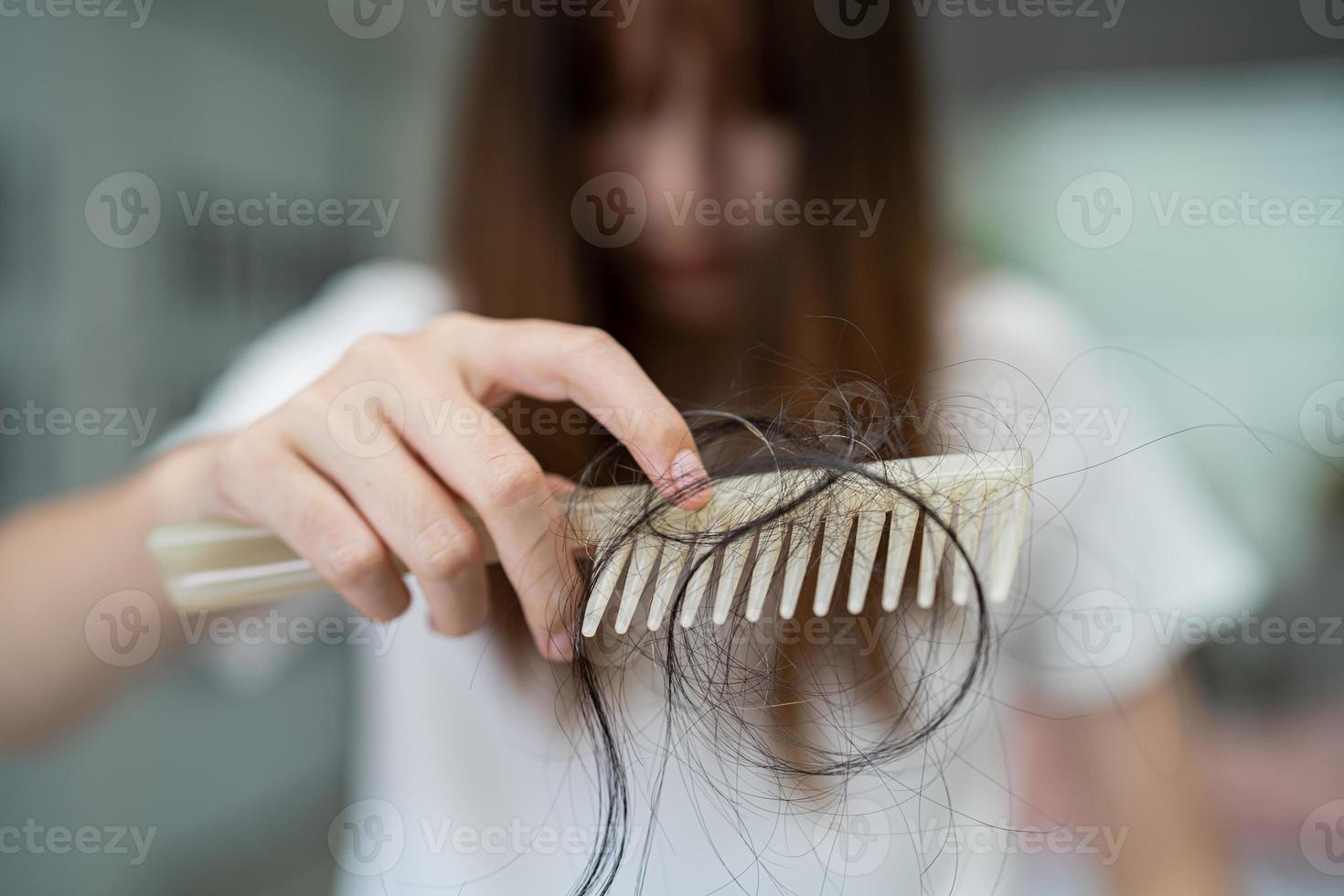 la donna asiatica ha problemi con la caduta dei capelli lunghi attaccata alla spazzola del pettine. foto