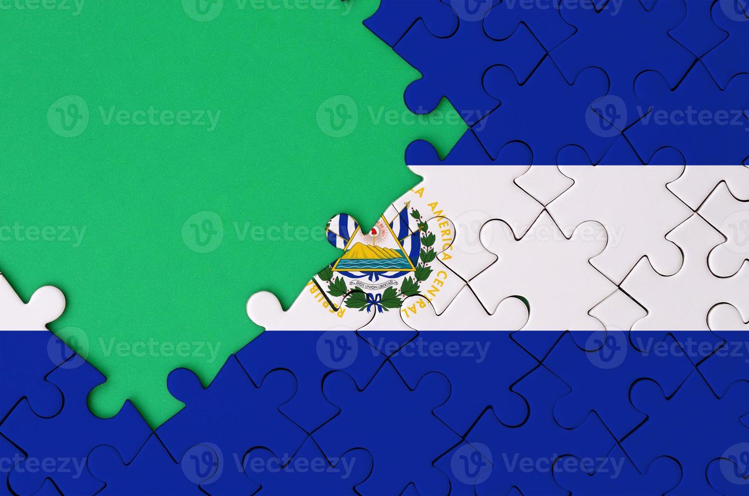 EL salvador bandiera è raffigurato su un' completato sega puzzle con gratuito verde copia spazio su il sinistra lato foto