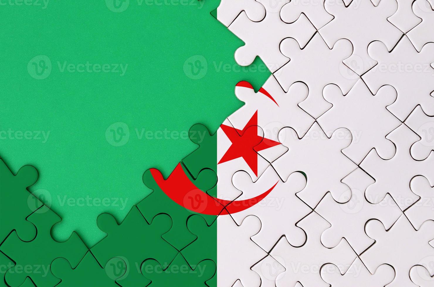 algeria bandiera è raffigurato su un' completato sega puzzle con gratuito verde copia spazio su il sinistra lato foto