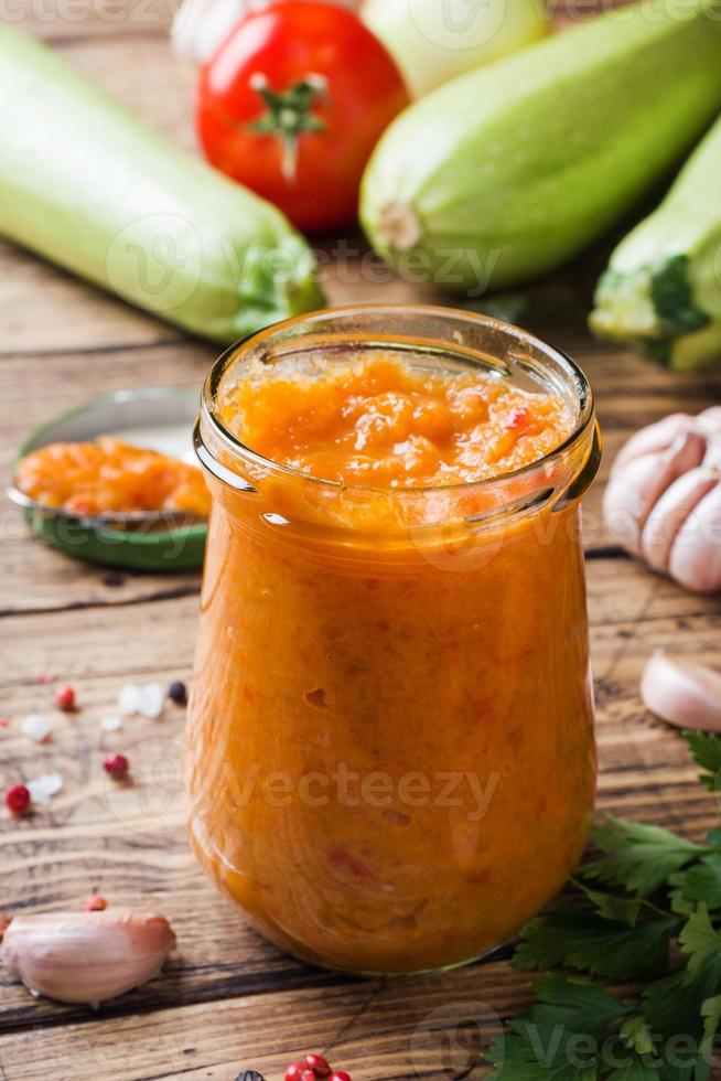 fatti in casa caviale a partire dal zucchine pomodori e cipolle nel un' bicchiere vaso su un' di legno sfondo. fatti in casa produzione conserve, in scatola in umido verdura. foto