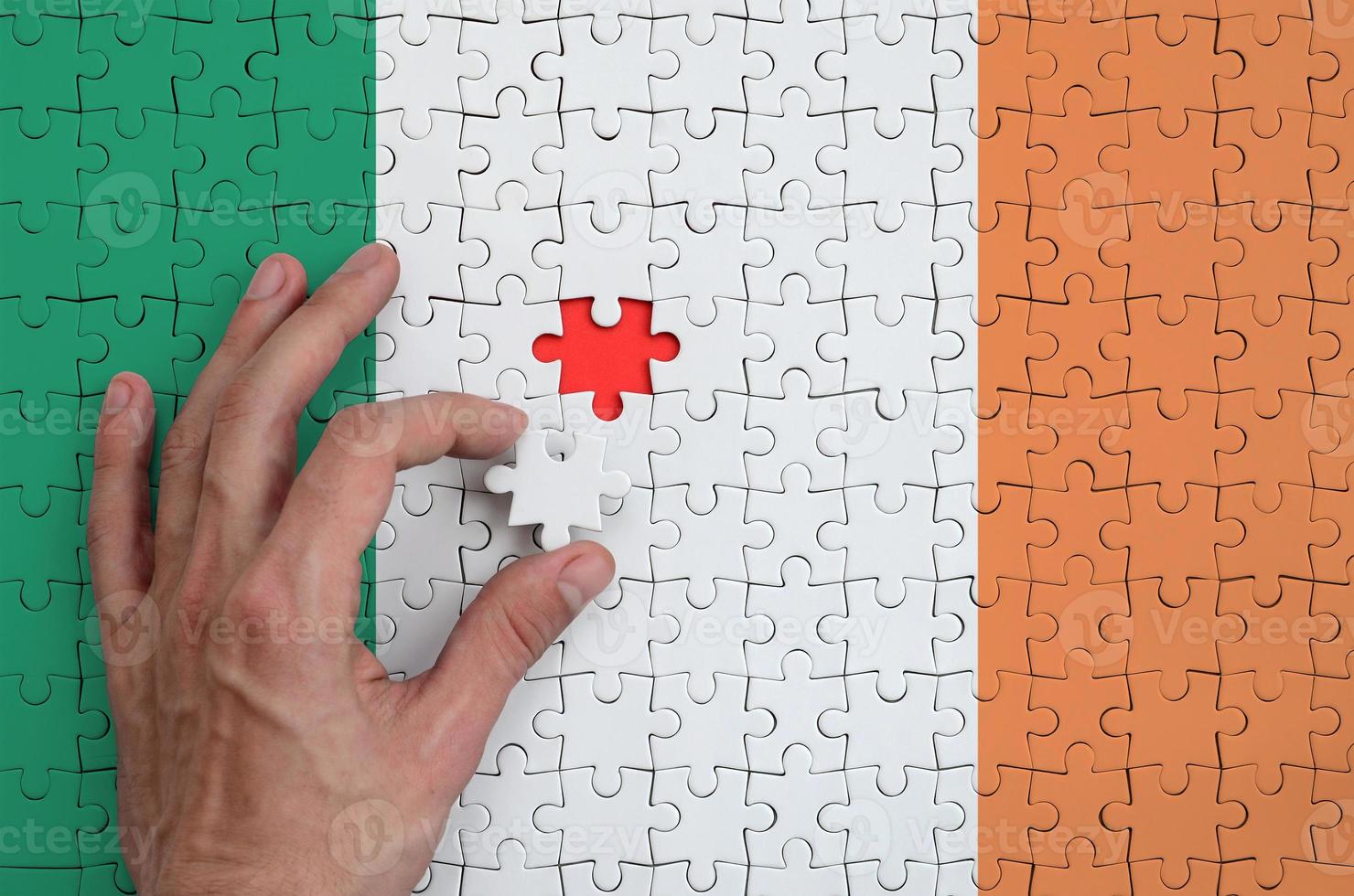 Irlanda bandiera è raffigurato su un' puzzle, quale il dell'uomo mano completa per piegare foto