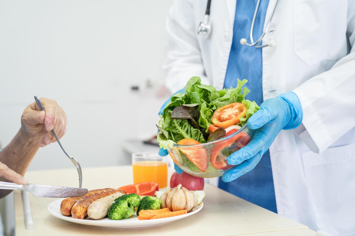 paziente asiatico anziano o anziano della donna che mangia colazione e cibo sano vegetale con speranza e felice mentre è seduto e affamato sul letto in ospedale. foto