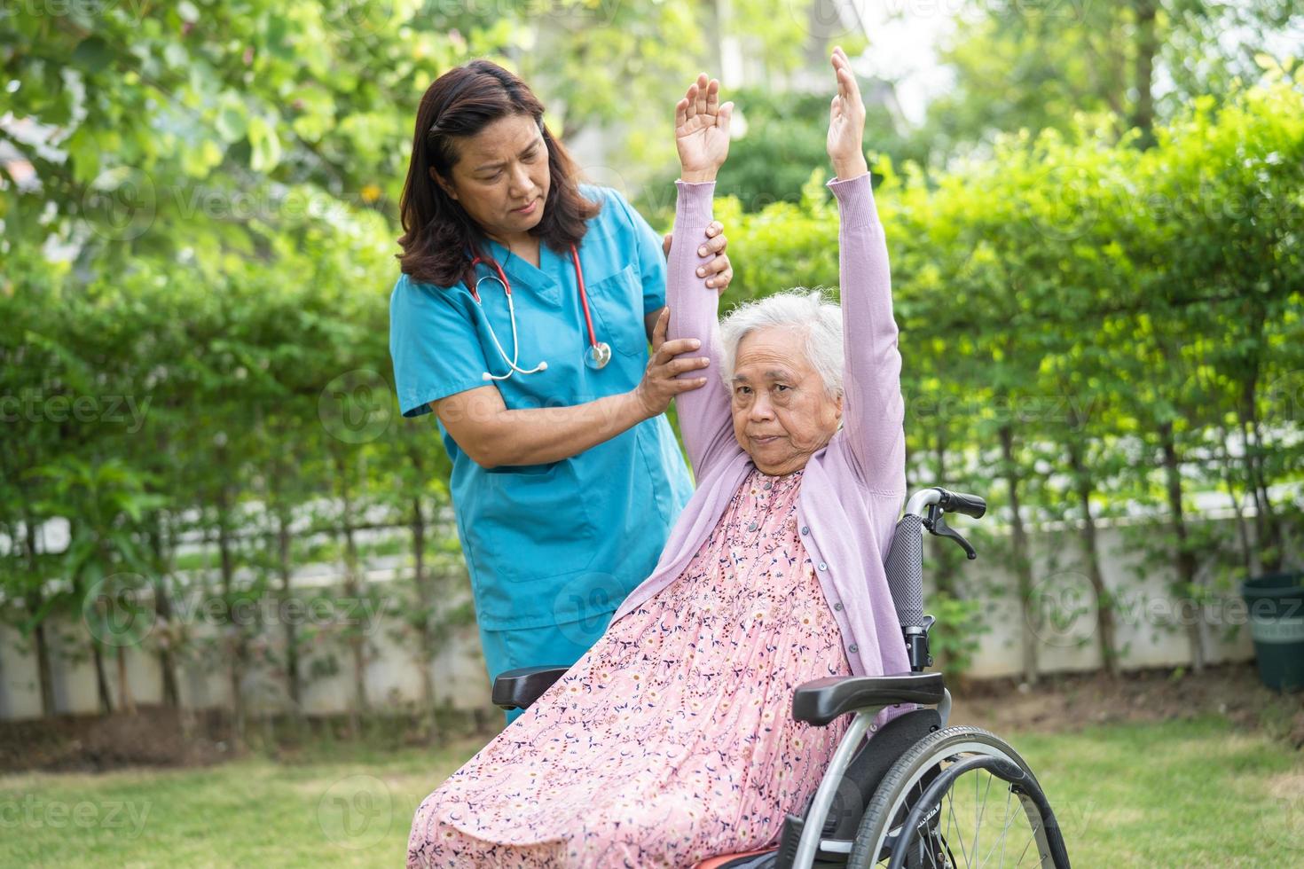 il medico aiuta l'esercizio del paziente della donna anziana anziana o anziana asiatica sulla sedia a rotelle con felice nel parco. foto