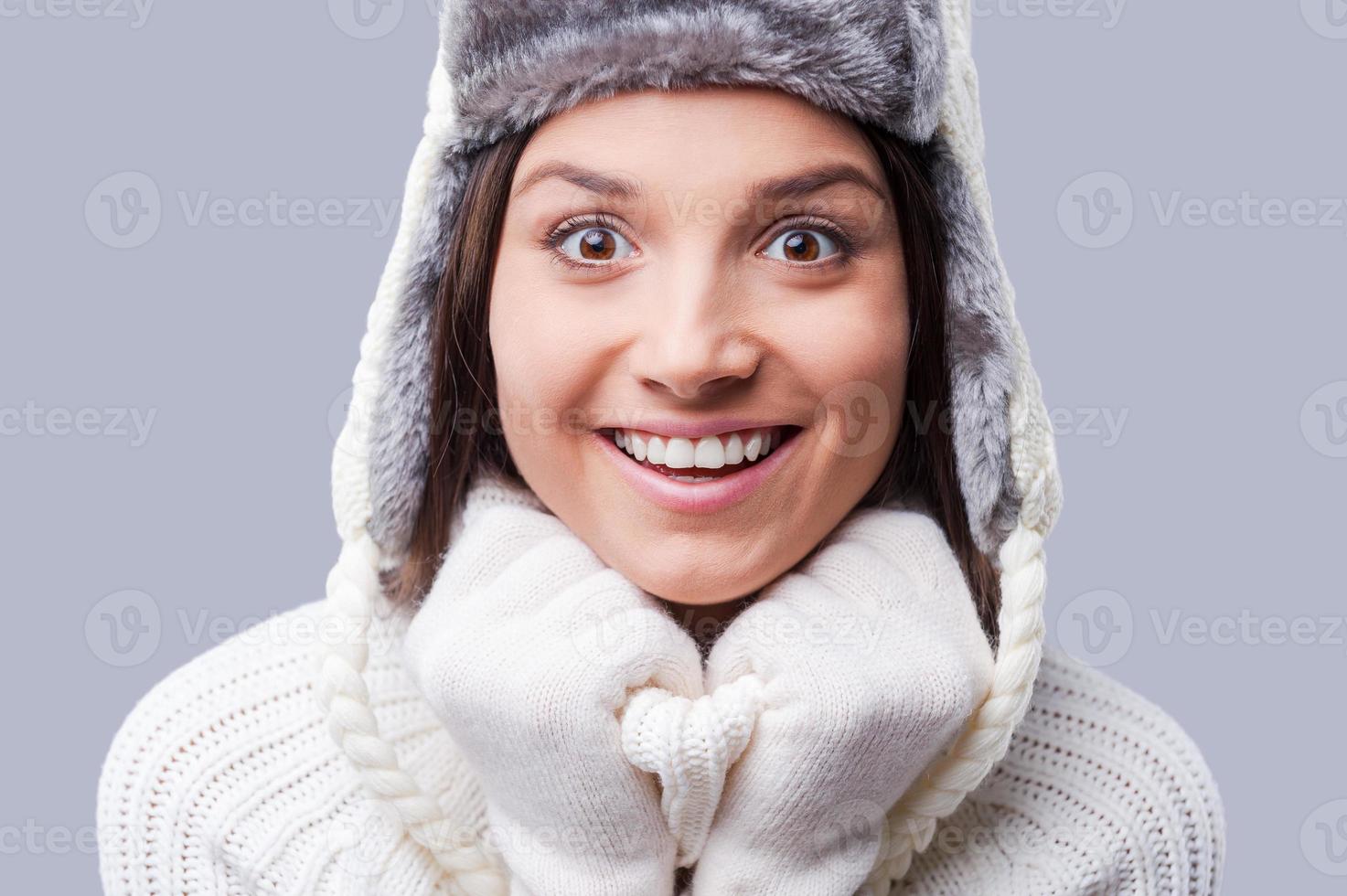 infine inverno arriva. contento giovane donne indossare caldo inverno capi di abbigliamento mentre in piedi contro grigio sfondo foto