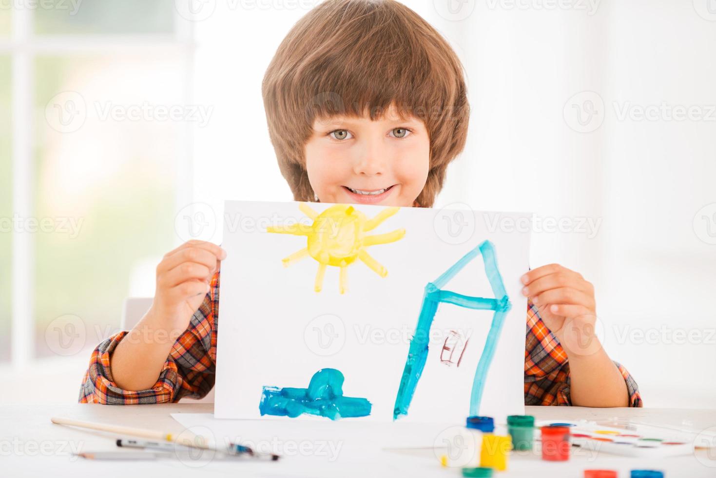 giovane artista. allegro poco ragazzo rilassante mentre pittura con acquerelli seduta a il tavolo foto