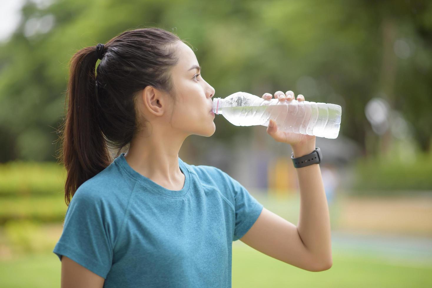 donna acqua potabile dopo l'allenamento in un parco foto