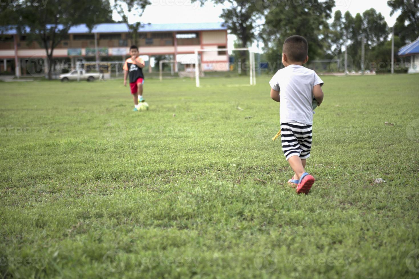 ragazzo Tenere un' calcio palla nel il suo mano a un' calcio campo poco bambini volere per giocare calcio. foto