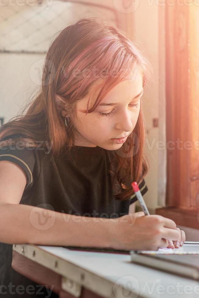 un' adolescenziale ragazza cavalcate un' treno. il ragazza scrive con un' matita nel un' taccuino. foto