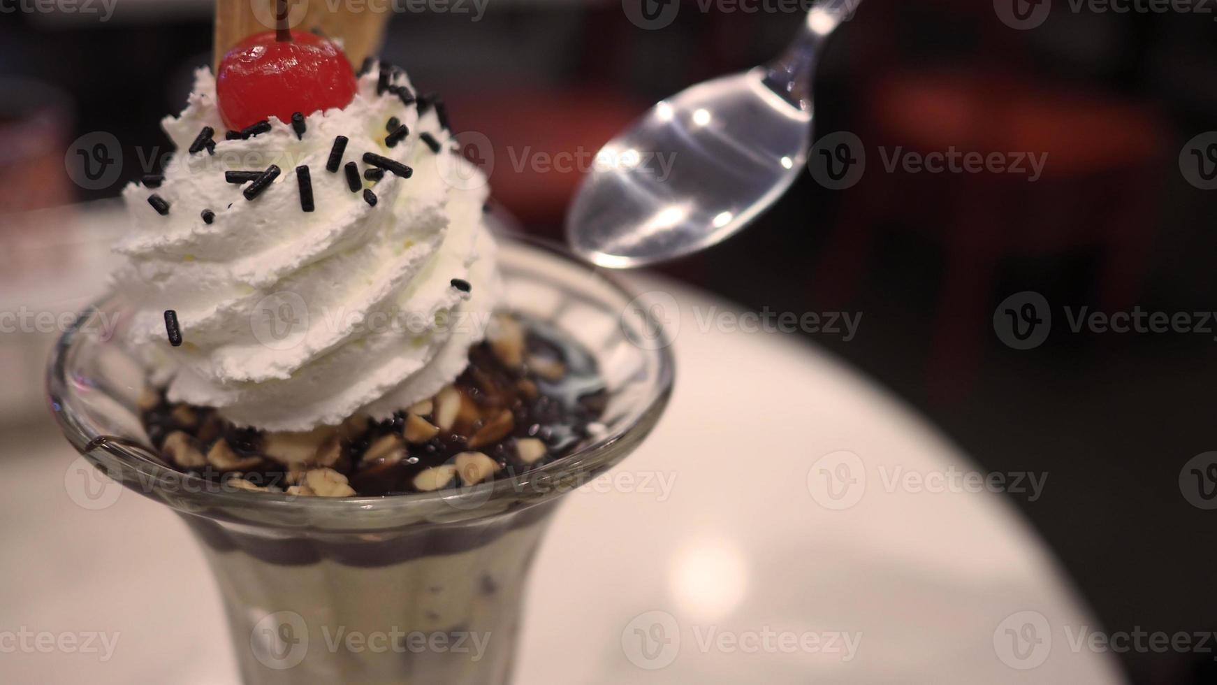 ghiaccio crema coppa di gelato guarnita con cucchiaio frusta crema e ciliegia vicino su foto