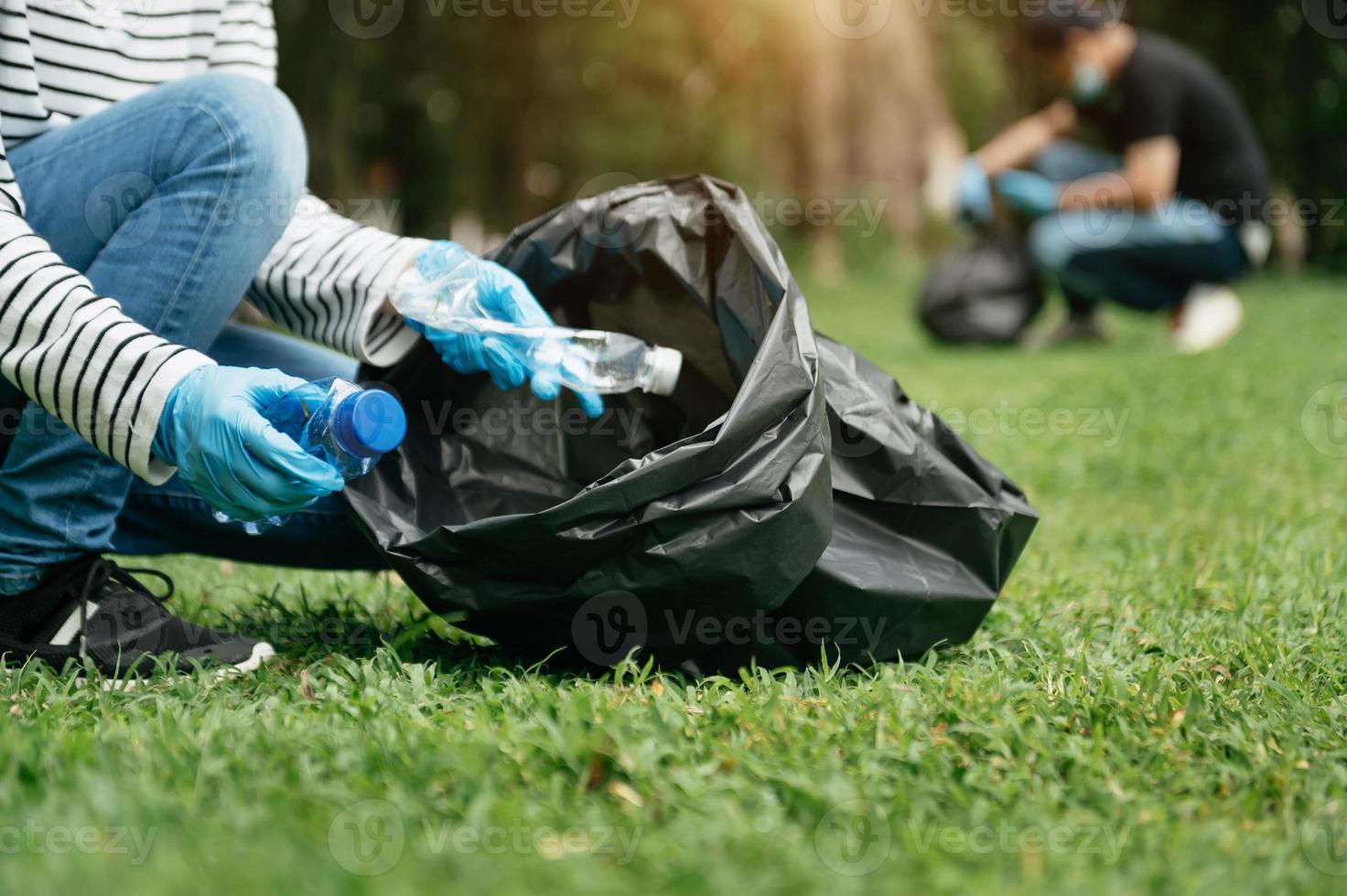 donna di mano scelte su plastica rifiuto per pulizia in riciclare Borsa per pulizia il parco. radura, inquinamento, ecologia e plastica concetto. foto