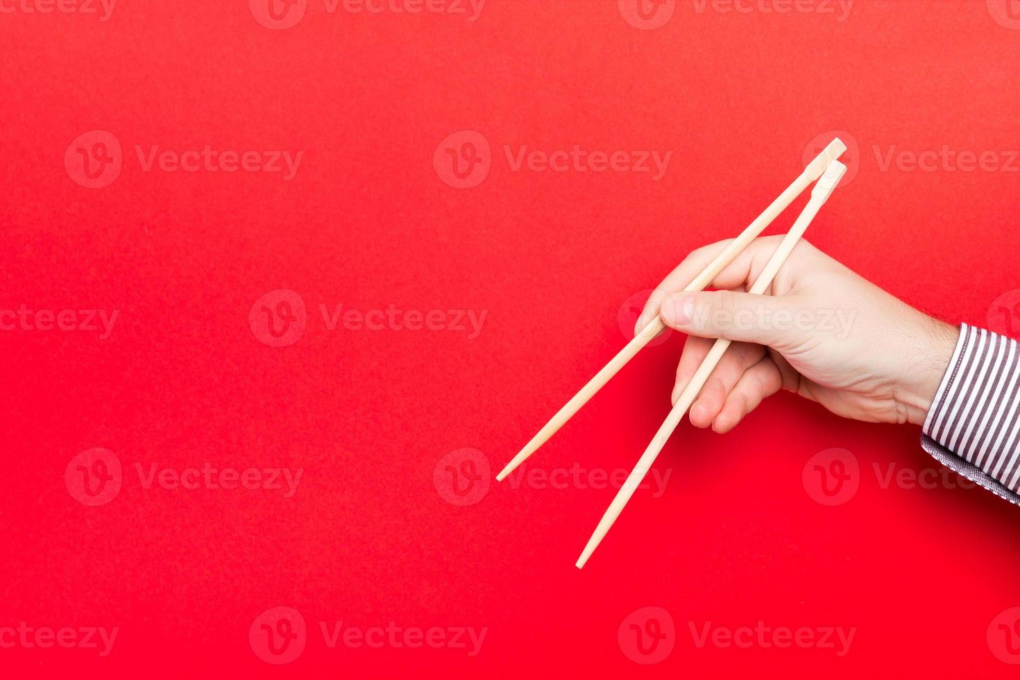 di legno bastoncini trattenuto con maschio mani su rosso sfondo. pronto per mangiare concetti con vuoto spazio foto