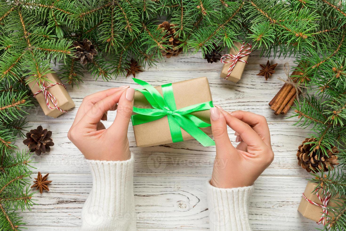 femmina mani Tenere fatto a mano presente scatola nel riciclato carta su bianca di legno tavolo sfondo. Natale preparazione concetto, regalo involucro sfondo foto