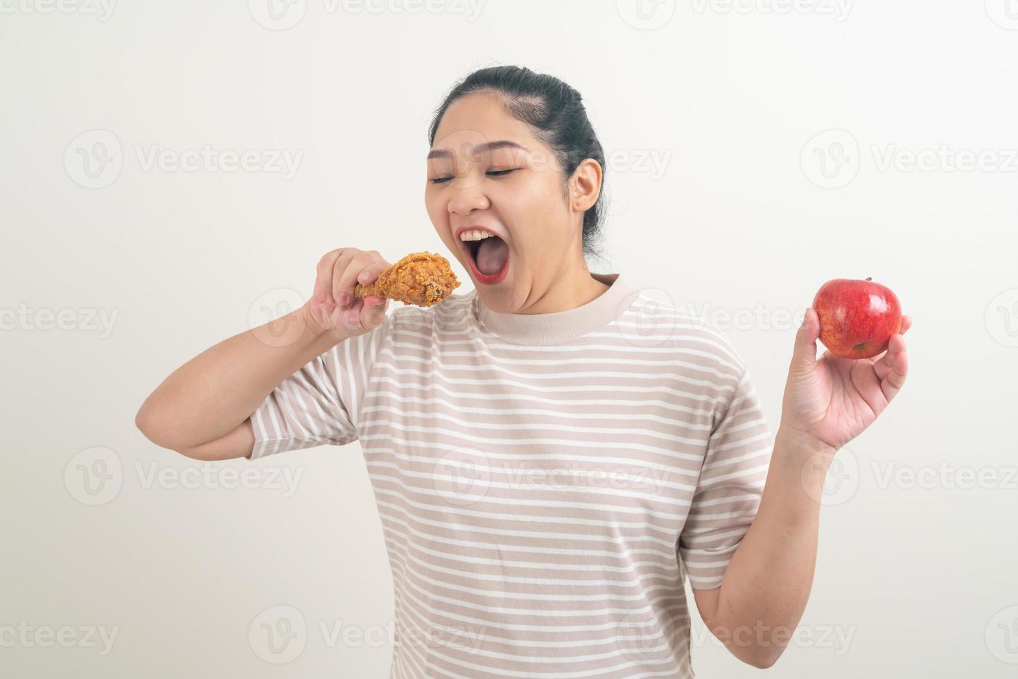 donna asiatica con pollo fritto e mela a portata di mano foto