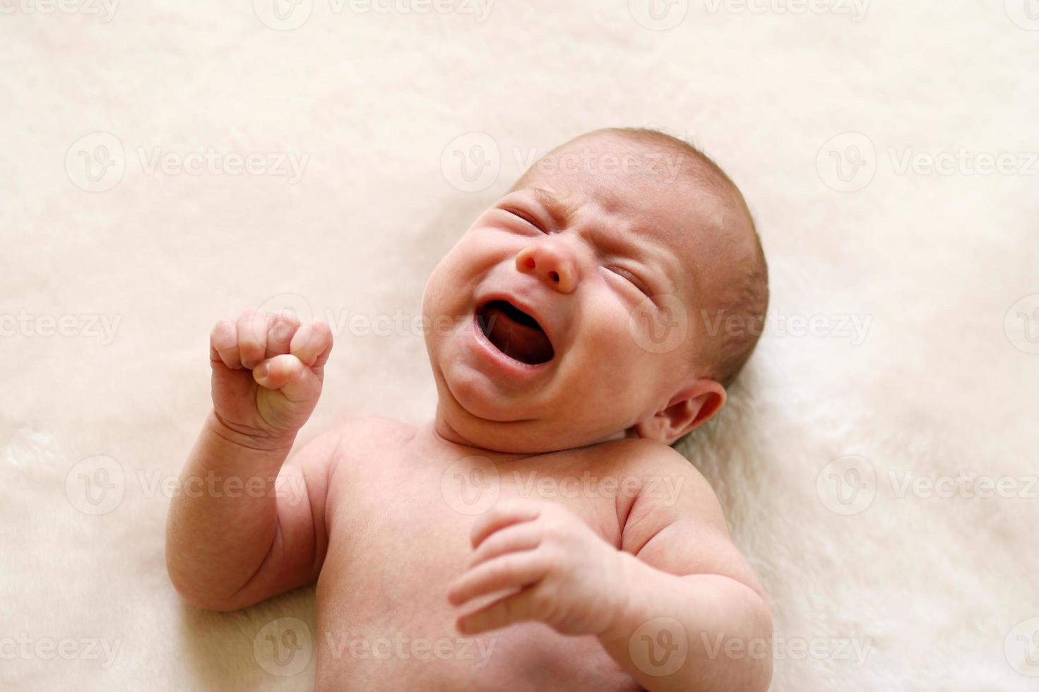 uno mese bambino è pianto con compressa pugni. foto