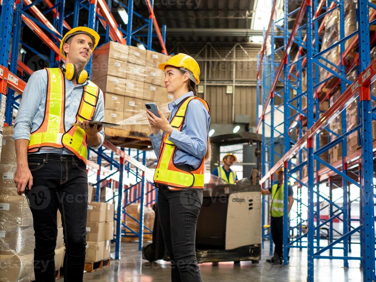 maschio femmina donna uomo giallo elmetto protettivo sicurezza Guarda smartphone mobile tavoletta tecnologia elettronico parlare parlare discussione scatola contenitore carrello elevatore a forca mezzi di trasporto carico fabbrica magazzino attività commerciale progetto foto