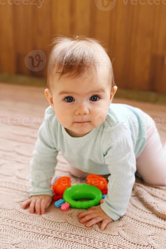 poco ragazza è seduta su un' beige a maglia plaid e giocando con luminosa colorato giocattolo. foto