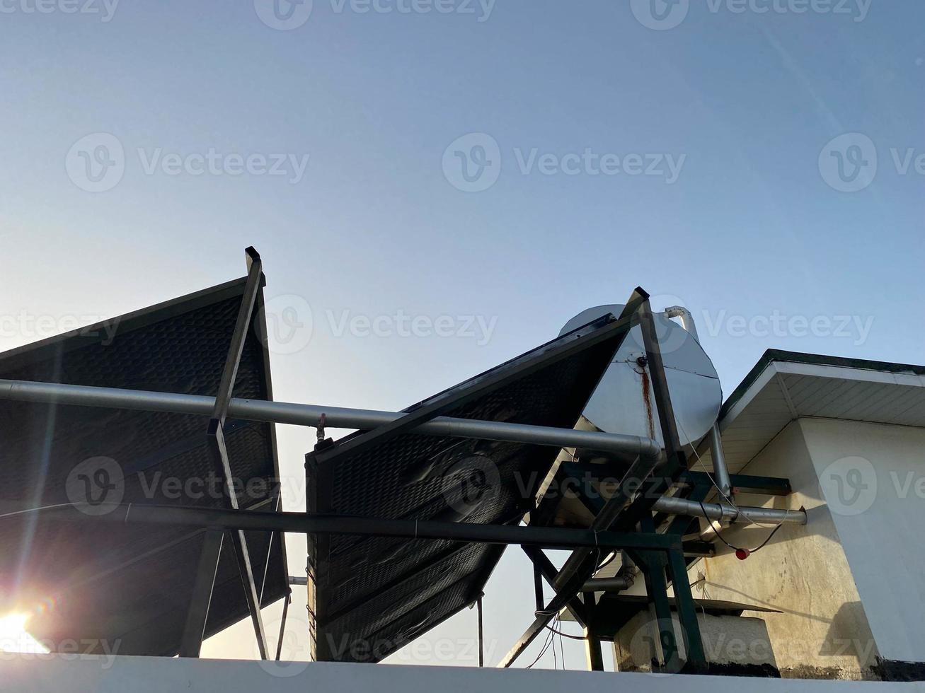 Visualizza di il tetto di un' edificio nel un' caldo tropicale nazione con solare pannelli e un' acqua serbatoio su il tetto. energia efficiente eco-friendly tecnologie foto