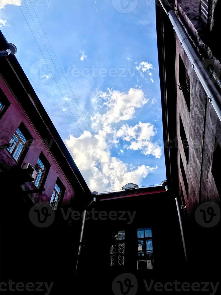 rosso edifici, un' accogliente cortile. un' rettangolare divario in quale il cielo è visibile. un' accogliente posto per appendere su nel un' bar. piccolo finestre Guarda a ogni altro foto