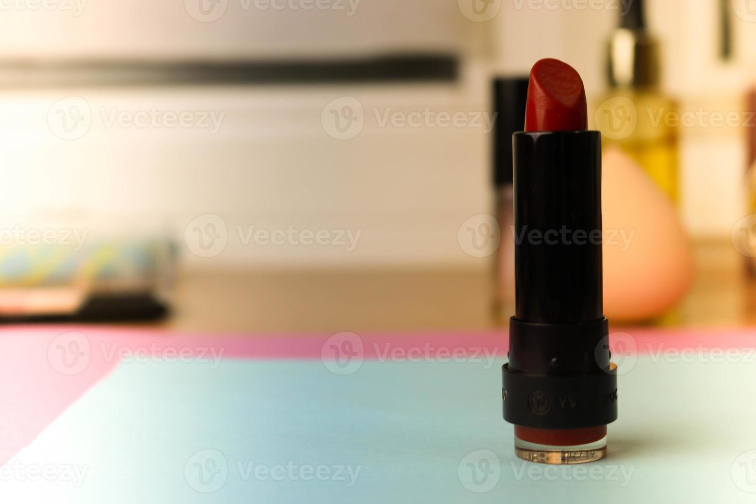rosso alla moda lipo labbro, e evidenziatore su il sfondo di un' bellezza trucco tavolo foto
