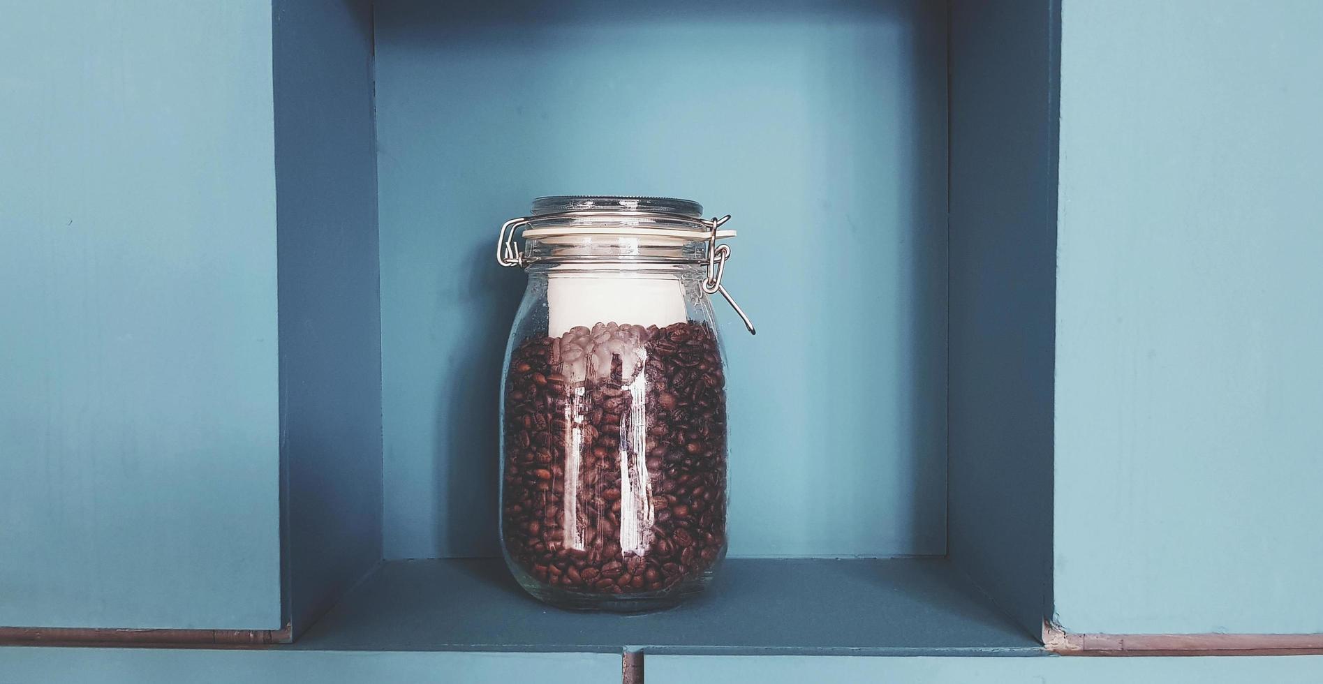 bicchiere bottiglia di caffè seme mettendo su verde di legno se stesso e parete sfondo per vendita o decorato a bar negozio nel Vintage ▾ tono. foto