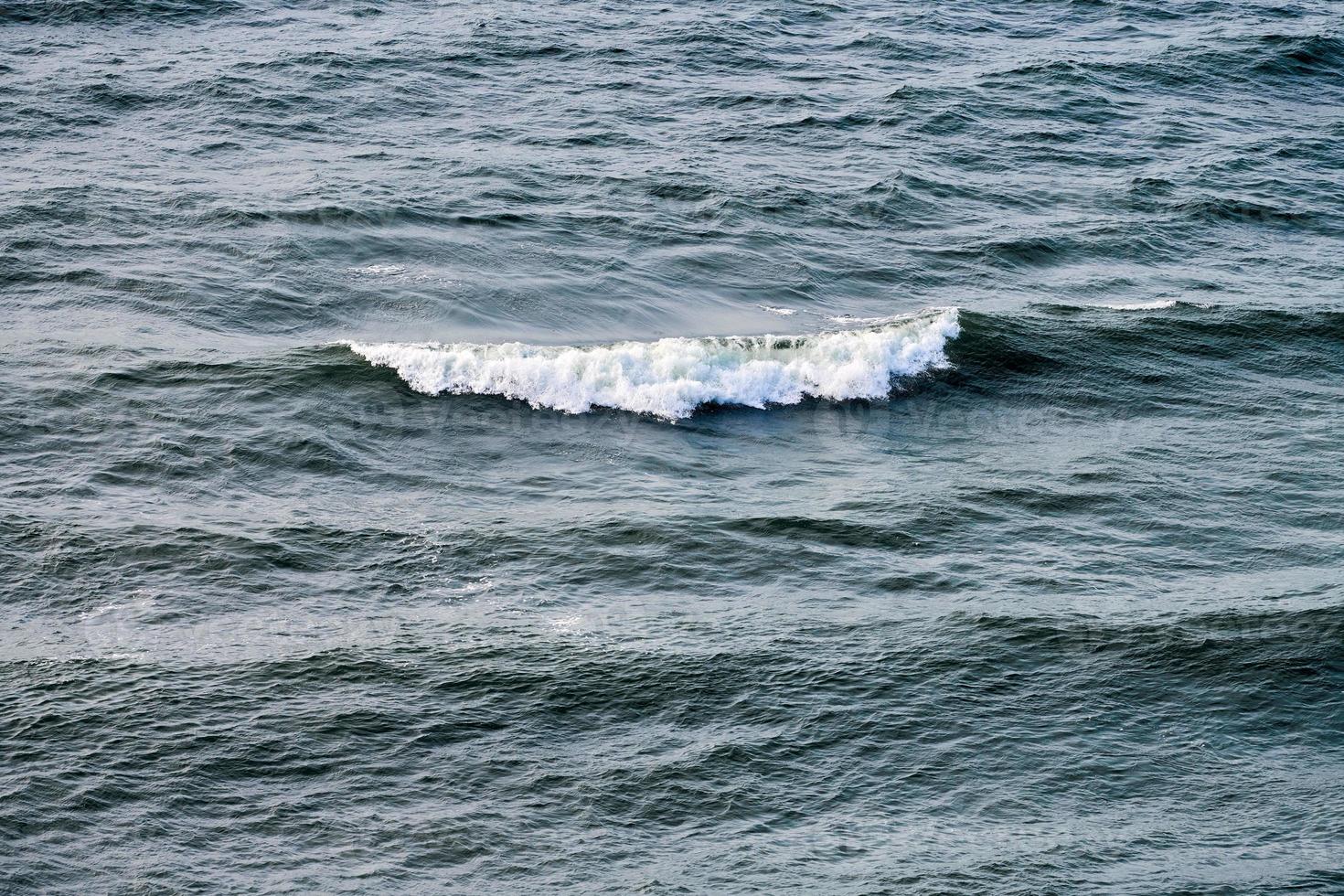 in profondità blu mare acque spruzzi con schiumoso onde, buio blu ondulato oceano acqua superficie, tempestoso mare foto