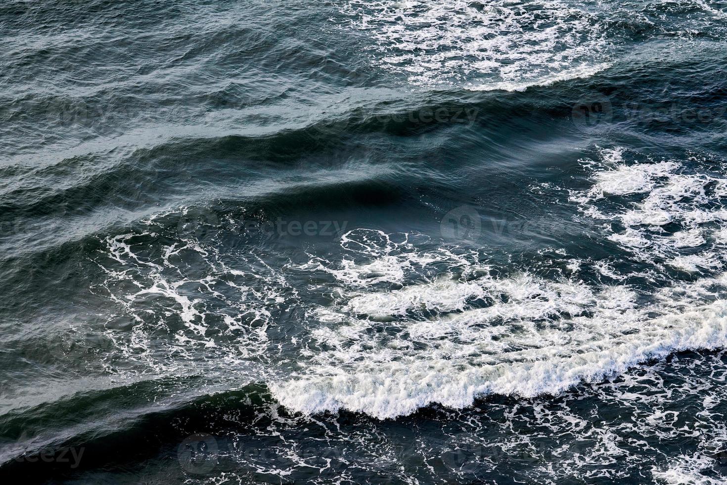 in profondità blu mare acque spruzzi con schiumoso onde, buio blu ondulato oceano acqua superficie, mare spray foto