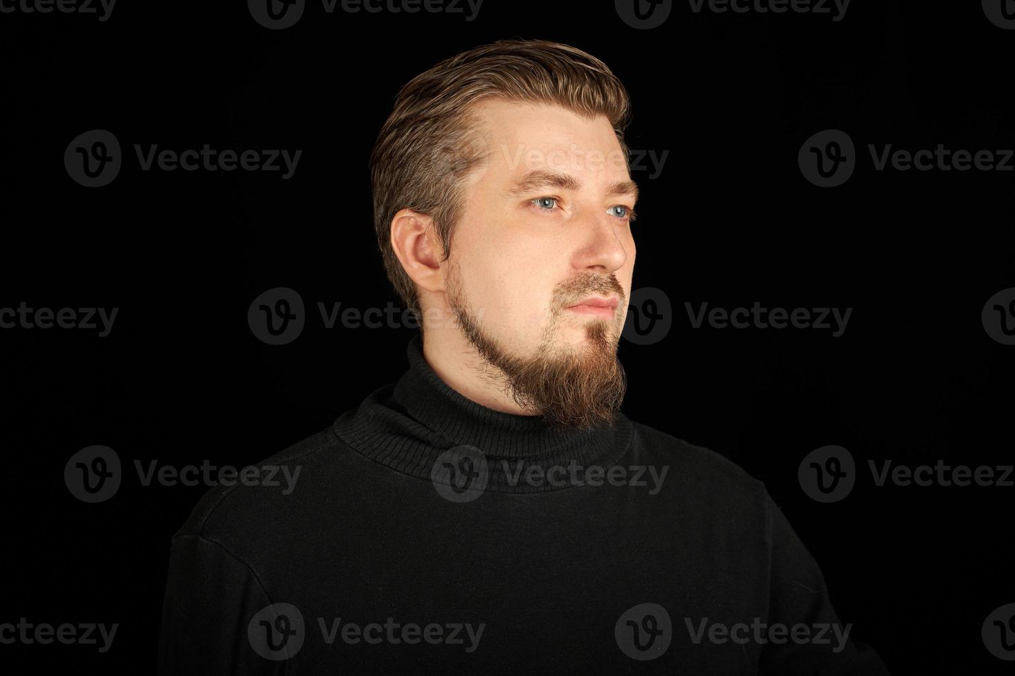 simpatico uomo barbuto, ritratto a mezzo profilo, sfondo nero foto