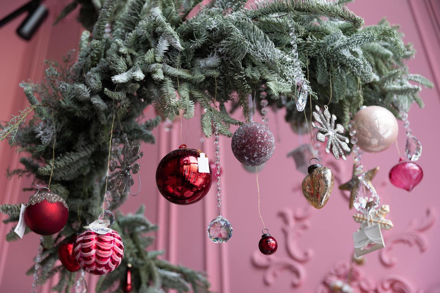 elegante Natale albero preparativi di naturale pino aghi e abete sospeso a partire dal il soffitto con Natale decorazioni contro il sfondo di un' rosa parete foto