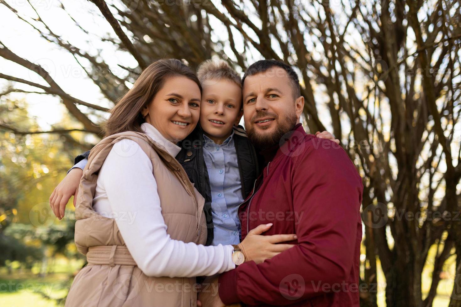 ritratto di contento mamma papà e figlio fra loro contro il fondale di un autunno parco foto