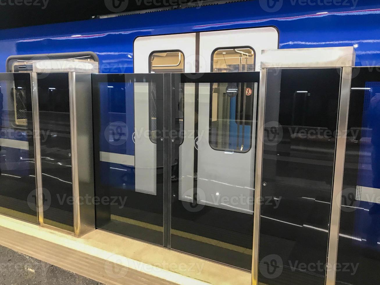 metropolitana con è aumentato sicurezza. nuovo la metropolitana stazioni. Doppio sicurezza, automatico porte prima entrata il treno. un' blu moderno treno con bicchiere porte arrivato su il modo. imbarco viaggiatori foto