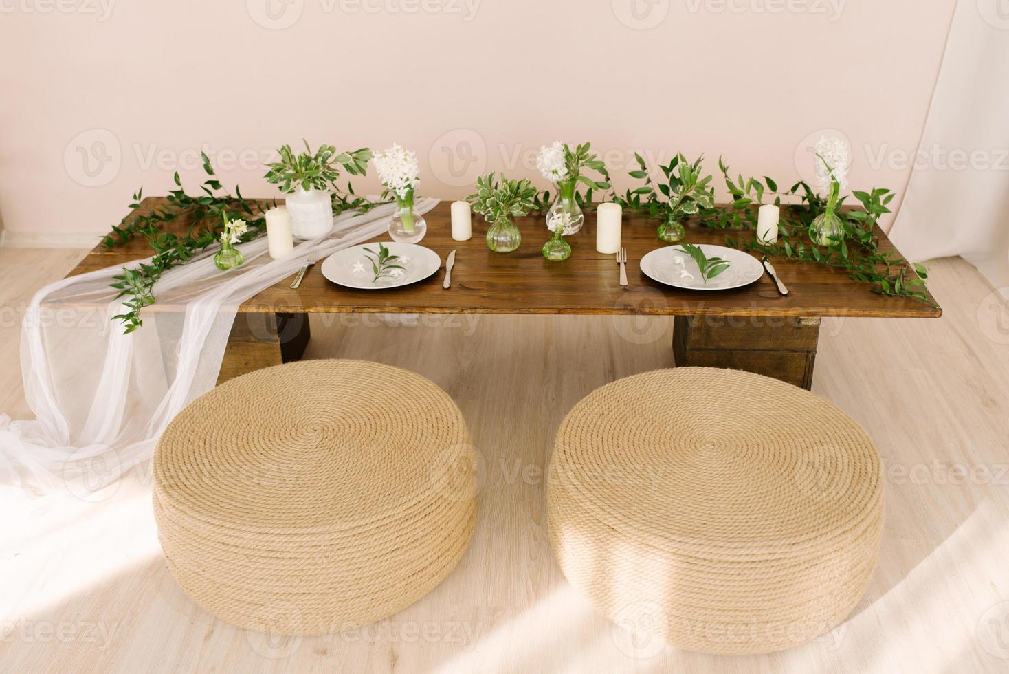 caffè tavolo nel boho o rustico stile, decorato e servito per un' vacanza o cena e ottomani coperto con corda nel il vivente camera nel il interno foto