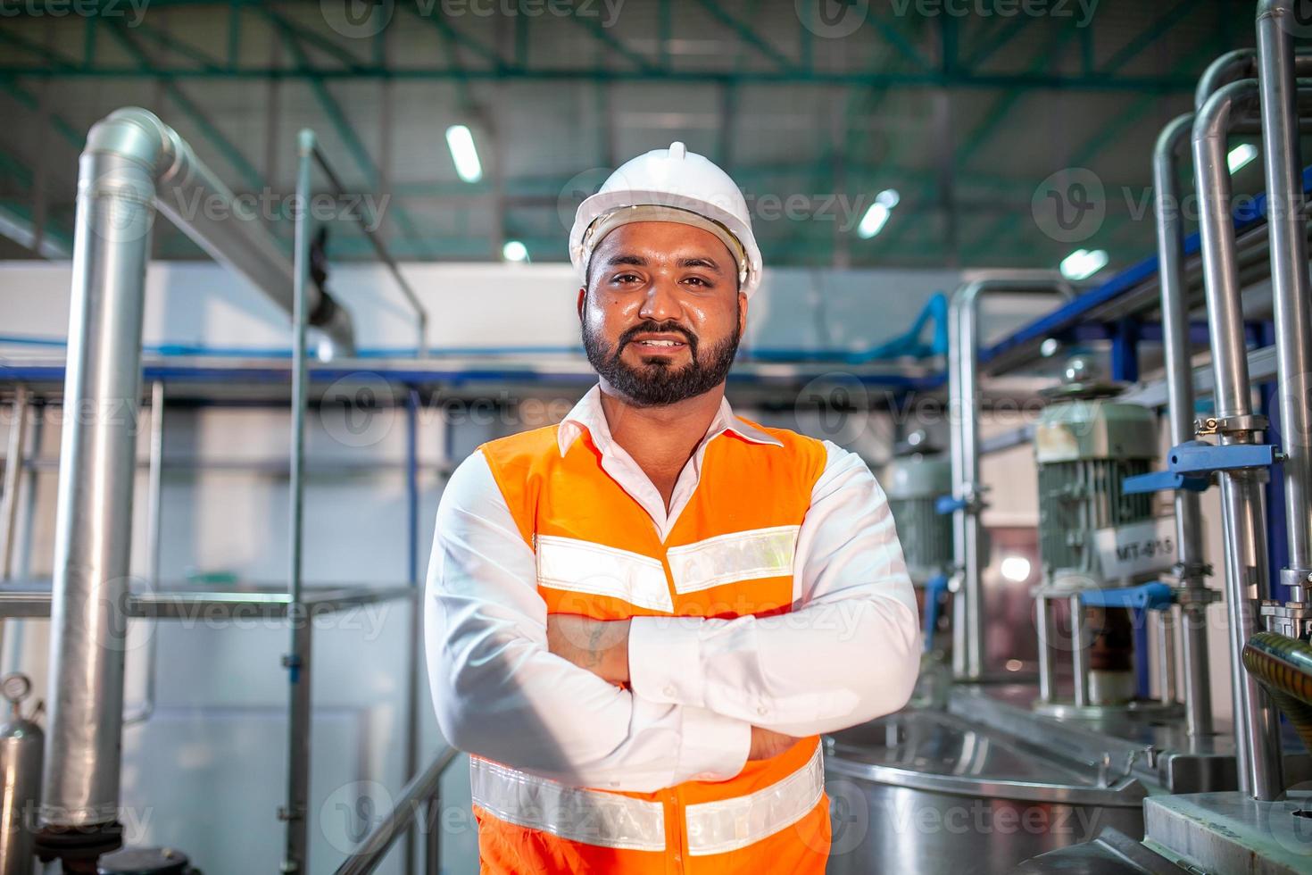 professionale ingegnere con casco lavori per mantenere industriale costruzione attrezzatura. lavoratore è in piedi nel il fabbrica con loro braccia incrociato. foto