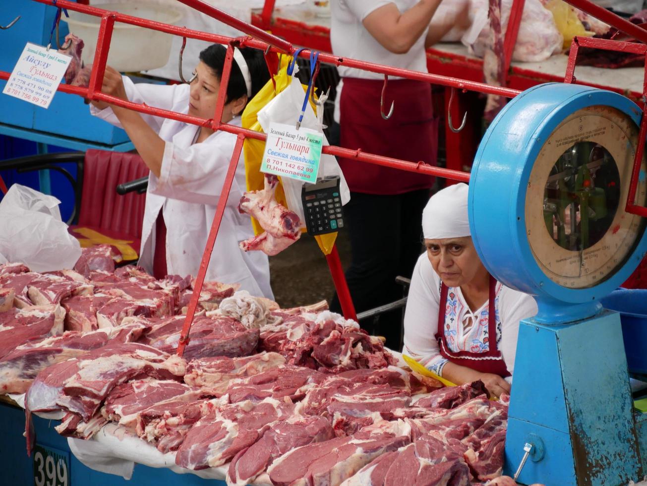 Almaty, kazakistan, 2019 - persone nel il carne sezione di il famoso verde bazar di Almaty, kazakistan, con merce su Schermo. foto