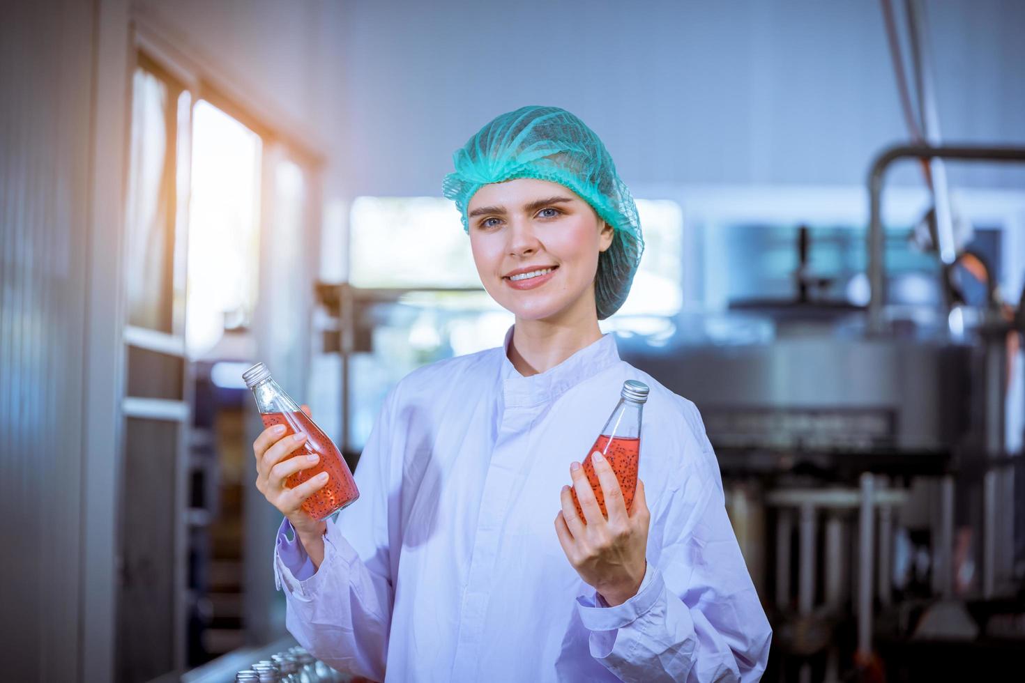 lavoratore di scienza nel bottiglia bevanda fabbrica indossare sicurezza cappello in posa mostrare opera per dai un'occhiata qualità di basilico seme produrre su trasportatore cintura prima distribuzione per mercato attività commerciale. foto