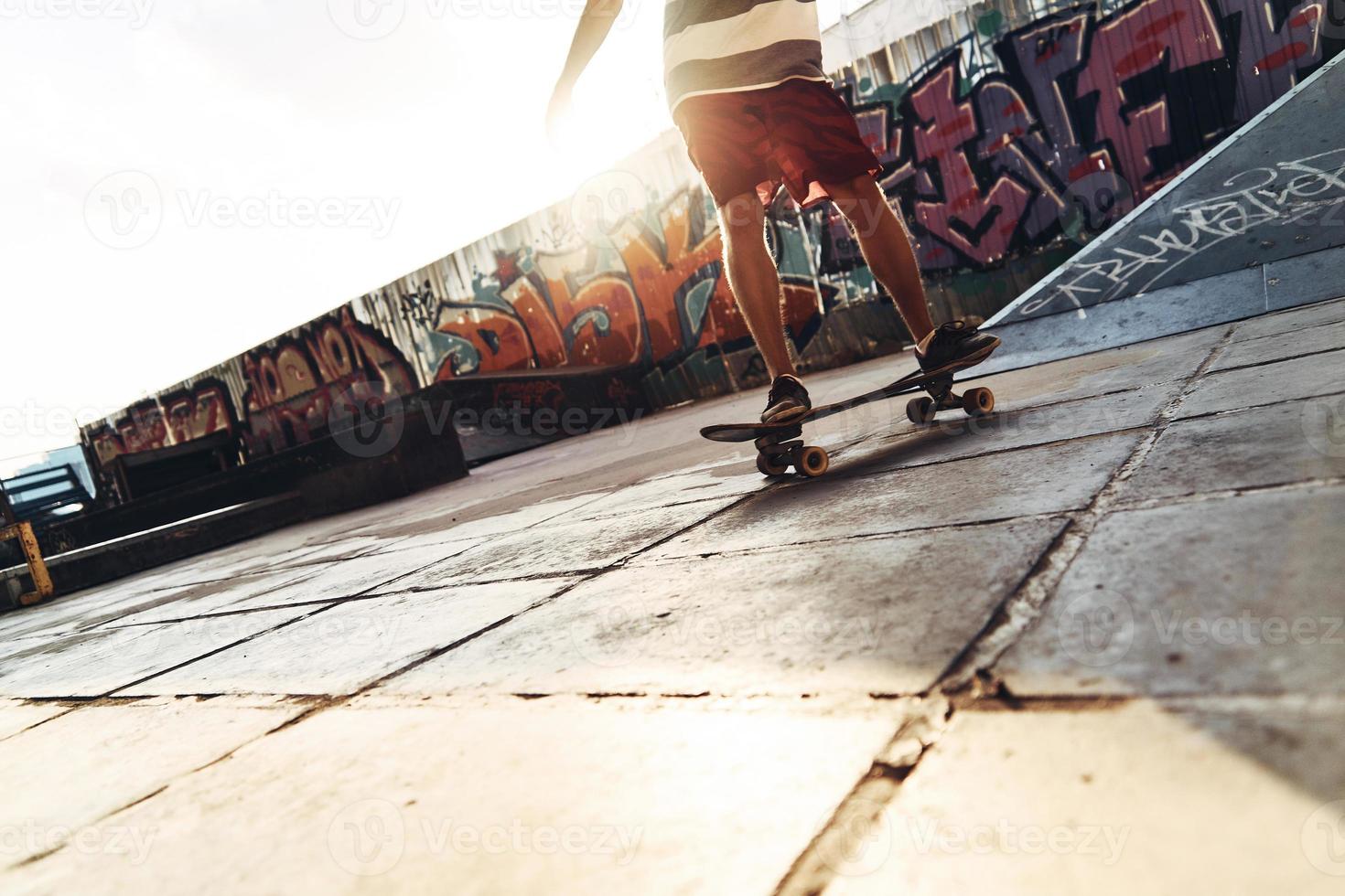 su il muoversi. avvicinamento di moderno giovane uomo andare con lo skateboard mentre sospeso su a il pattinare parco all'aperto foto